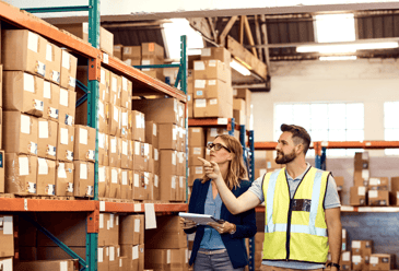 Two warehouse managers examining inventory and discussing the integration of RFID technology with their warehouse management system for improved efficiency and accuracy.